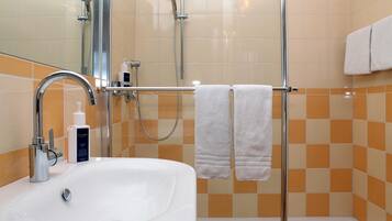 Un bagno con un lavandino bianco, un box doccia in vetro e un portascopevoli con due asciugamani.