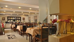 Un restaurante con varias mesas, sillas y una zona de bar.