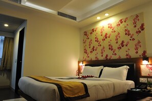 Een hotelkamer met een bed, een nachtkastje met een lamp en bloemenbehang.