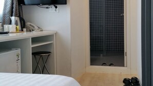 A hotel room with a bed, a desk with a flat-screen TV, a telephone, and a shoe rack. - Won's Ville Myeongdong (Seoul)