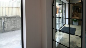 A hallway with a glass door leading to an outdoor area, a metal gate, and a small indoor plant. - Won's Ville Myeongdong (Seoul)