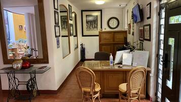 A kitchen with a dining area, featuring a sewing machine, wicker chairs, a clock, and framed pictures on the walls.