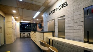A K-pop hotel interior with a wooden reception desk, bar area, and seating. - KSTAR Metro Hotel (Seoul)