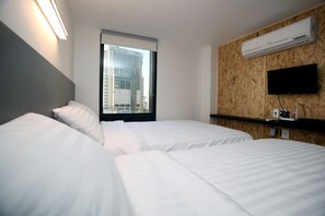 A hotel room with two beds, a large window with a city view, an air conditioning unit, and a mounted television. - KSTAR Metro Hotel (Seoul)