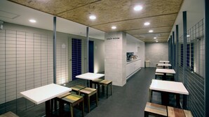 A modern interior with multiple tables and benches, a kitchen area, and a 'COZY ROOM' sign. - KSTAR Metro Hotel (Seoul)