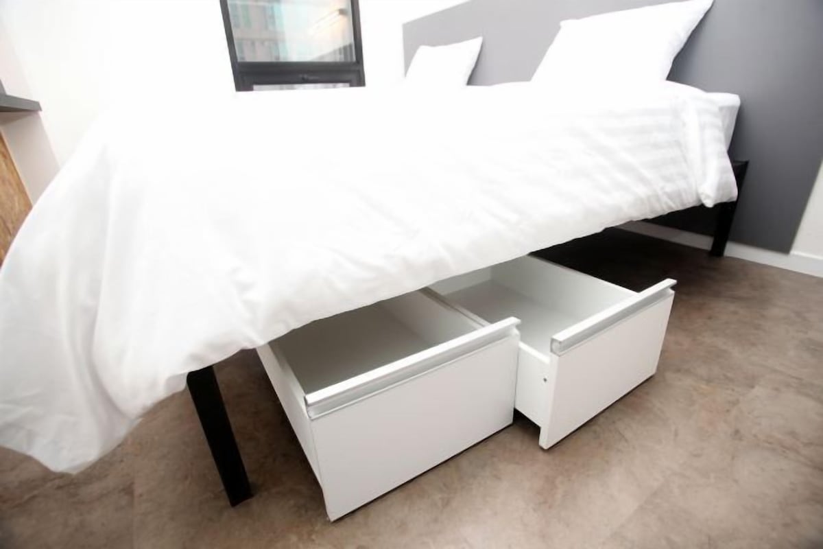 Una cama con un edredón blanco y dos cajones blancos debajo.