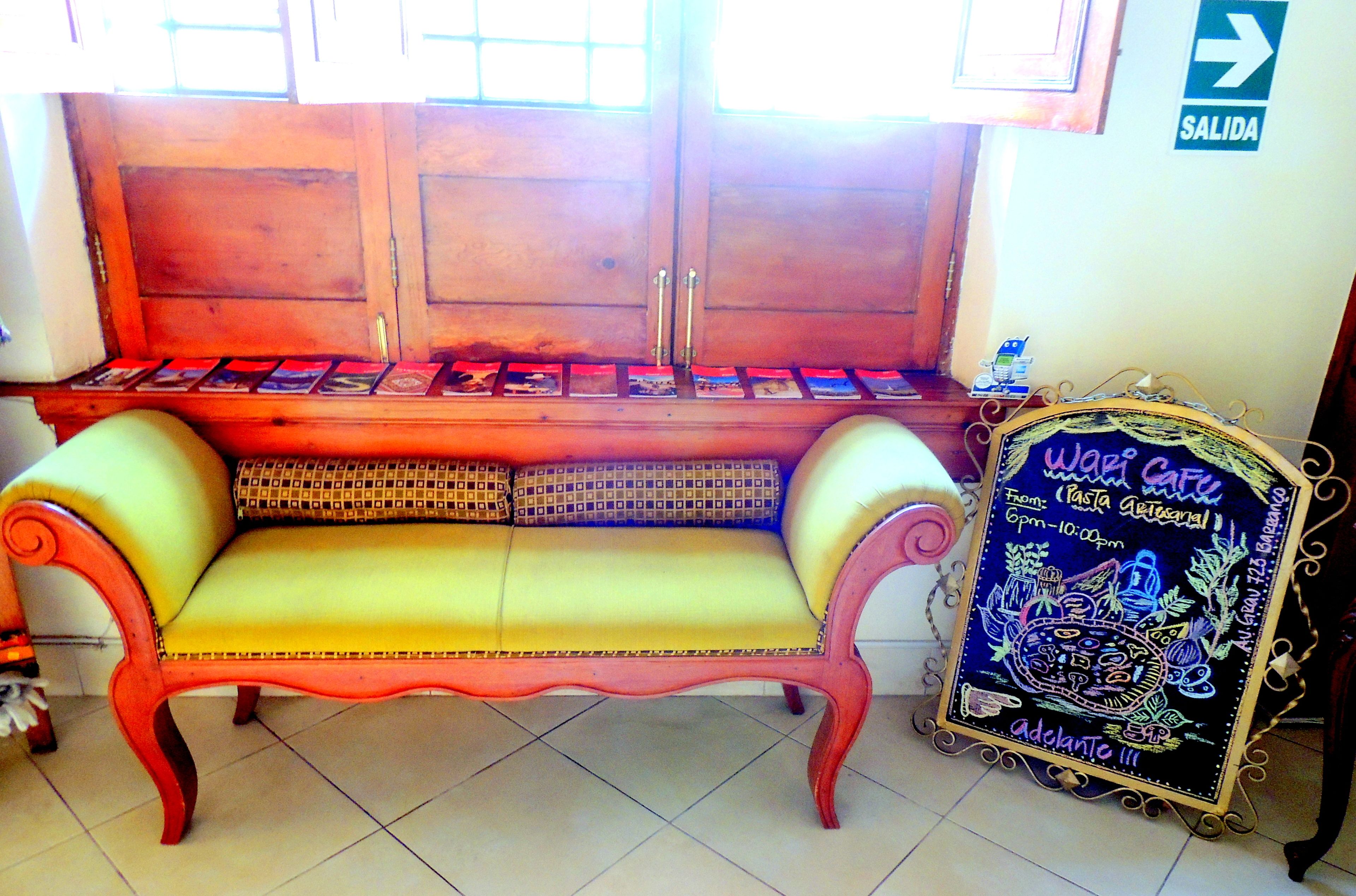 A wooden bench with cushioned seats and a chalkboard sign advertising a cafe.