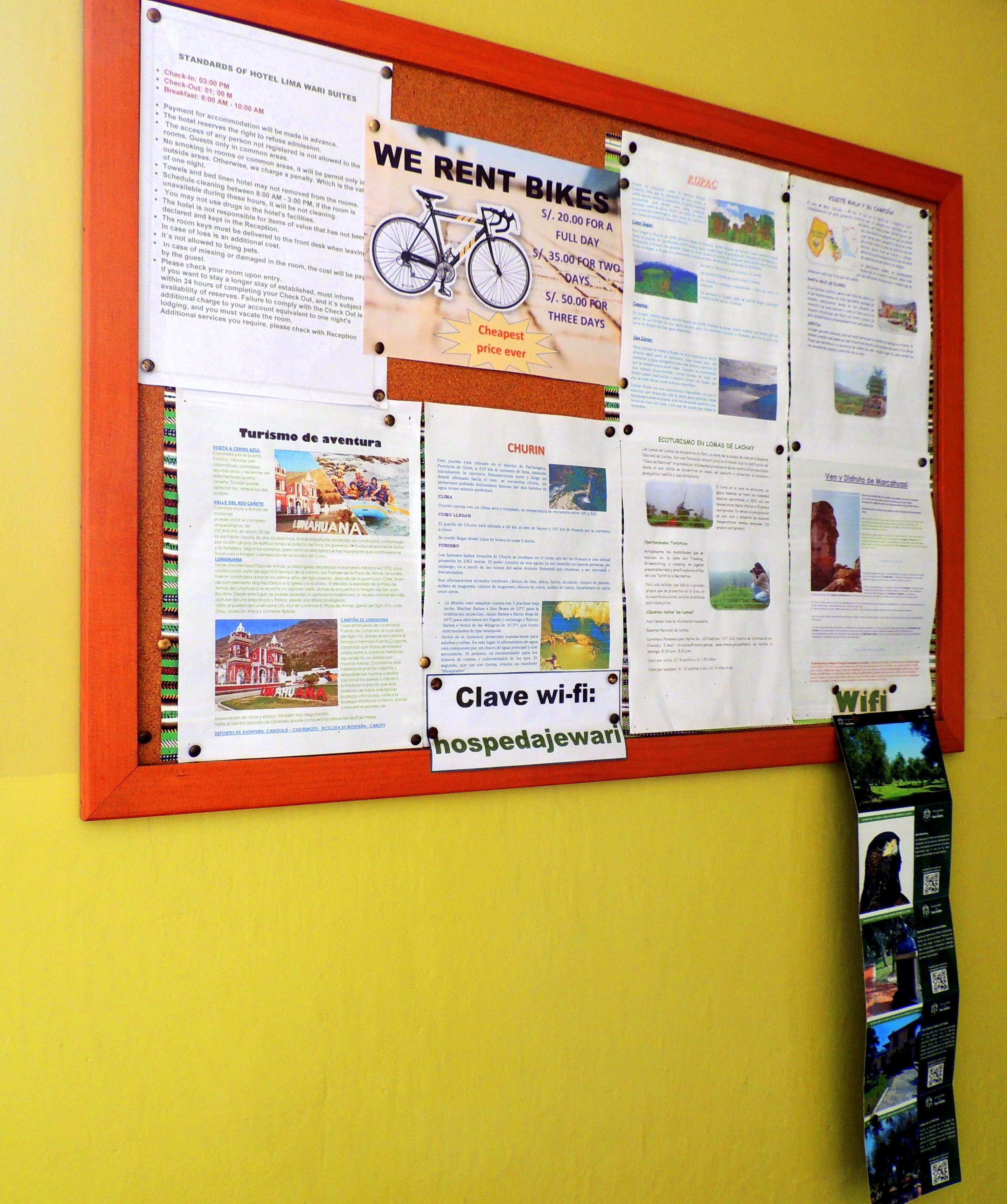 A bulletin board with various informational posters, including details on hotel standards, bike rental, and local attractions.