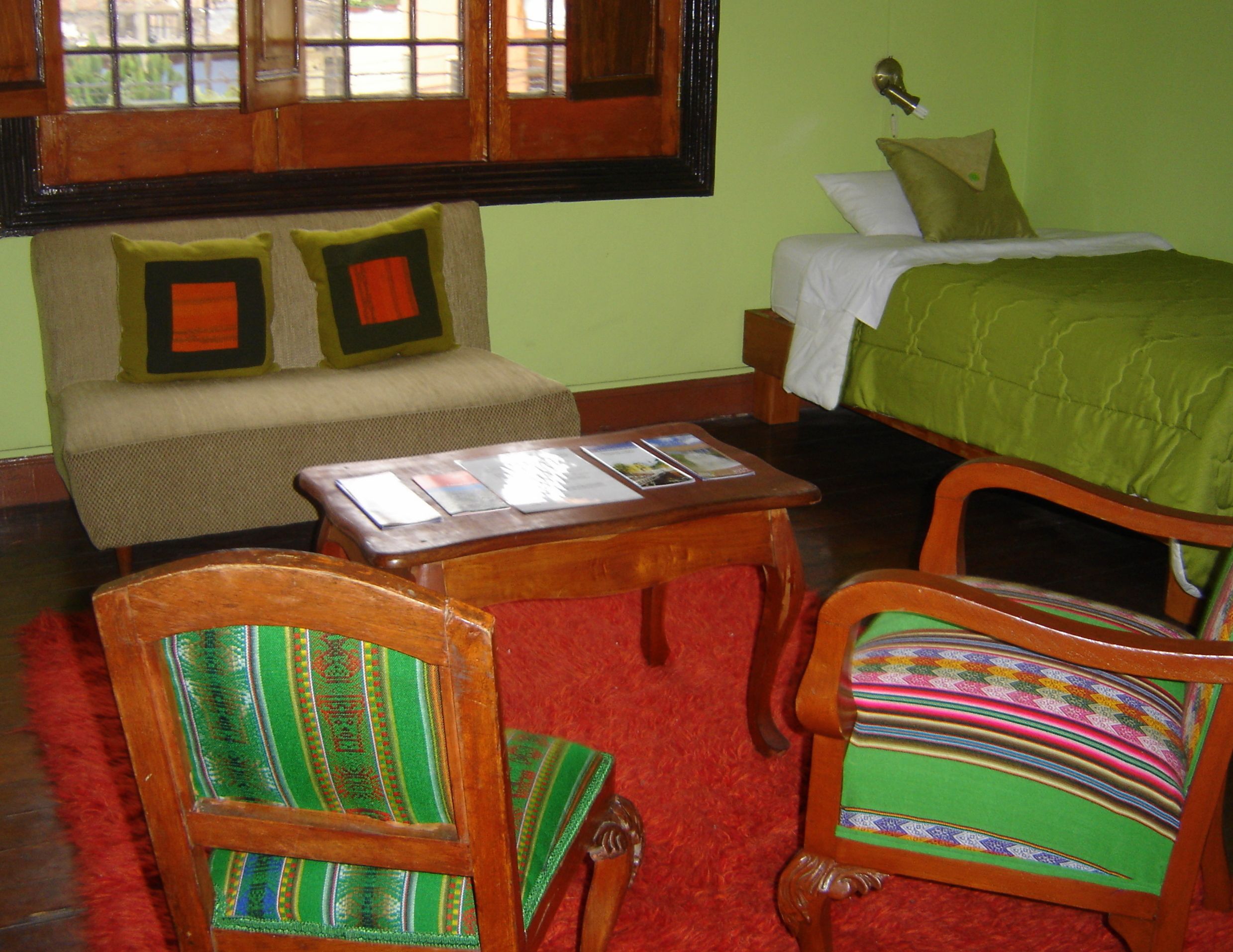 A room with a bed, a sofa, a table, and two chairs.