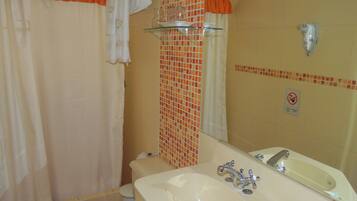 Un baño con bañera, lavabo con espejo e inodoro.