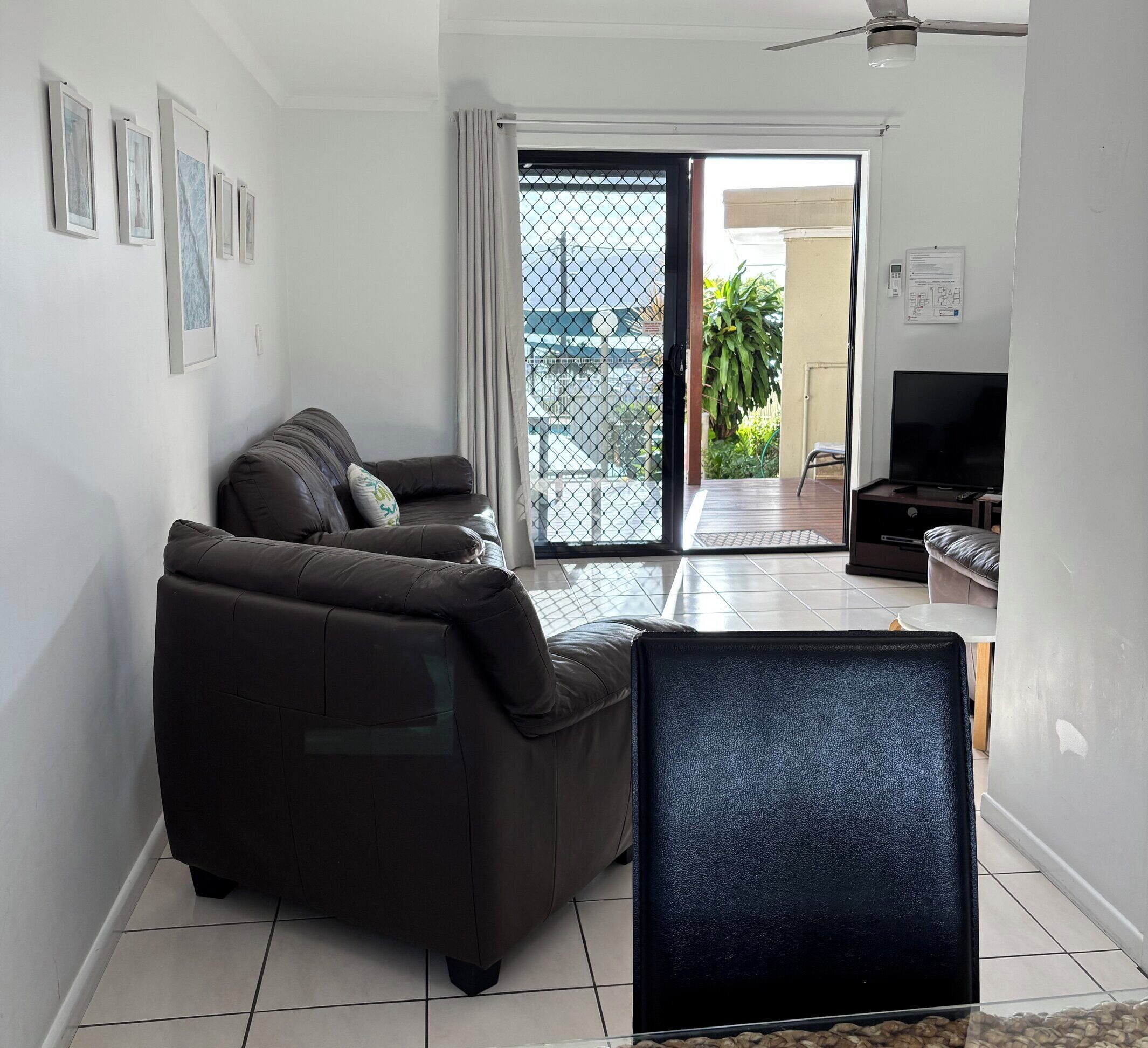 A living room with a sofa, a TV, and a sliding glass door leading to a balcony.