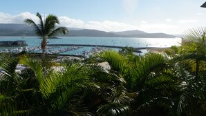 A marina with boats, a clear sky, and mountains in the background.
