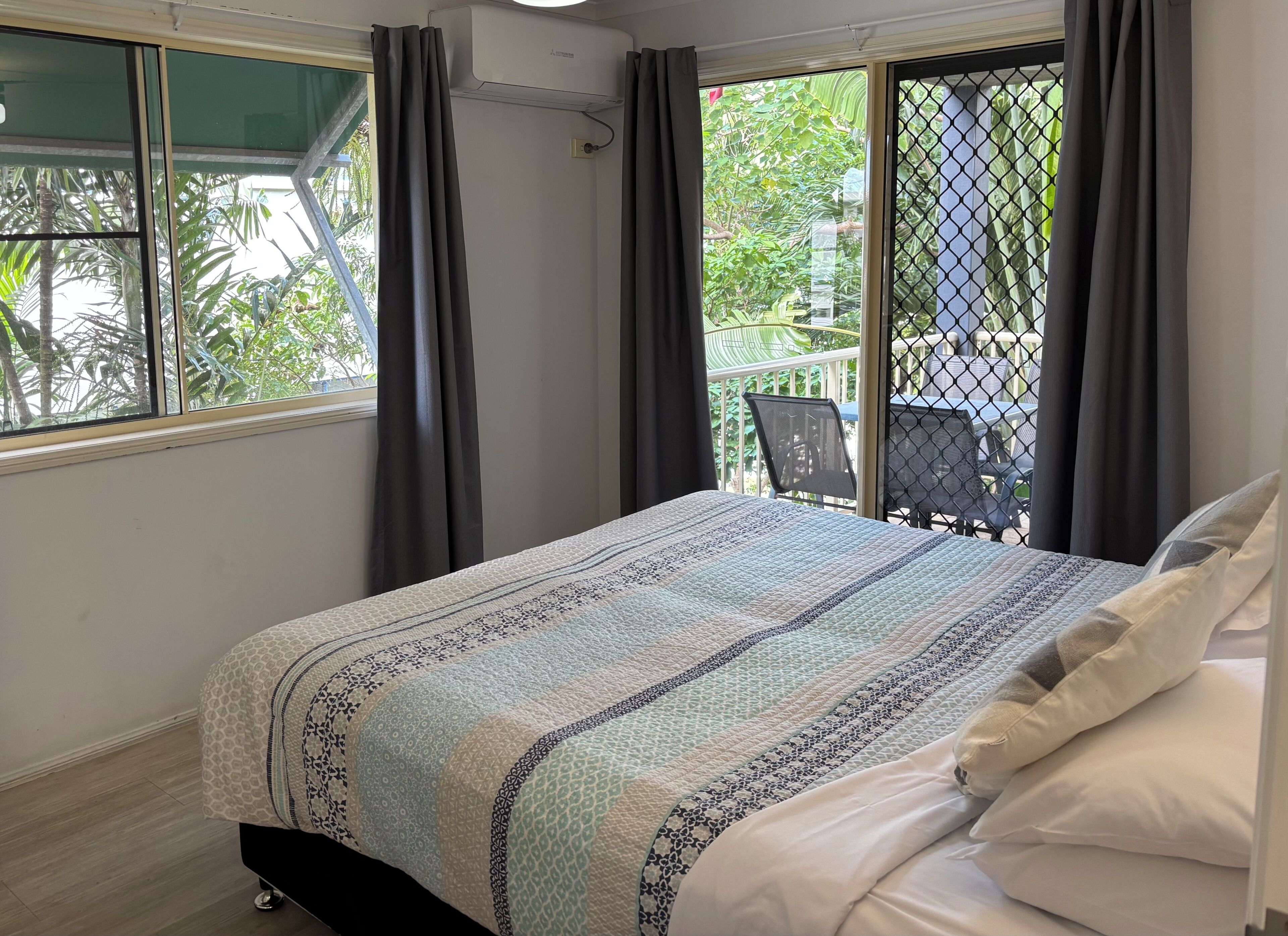 Un dormitorio con cama, ventana con cortinas y vistas a mobiliario exterior.