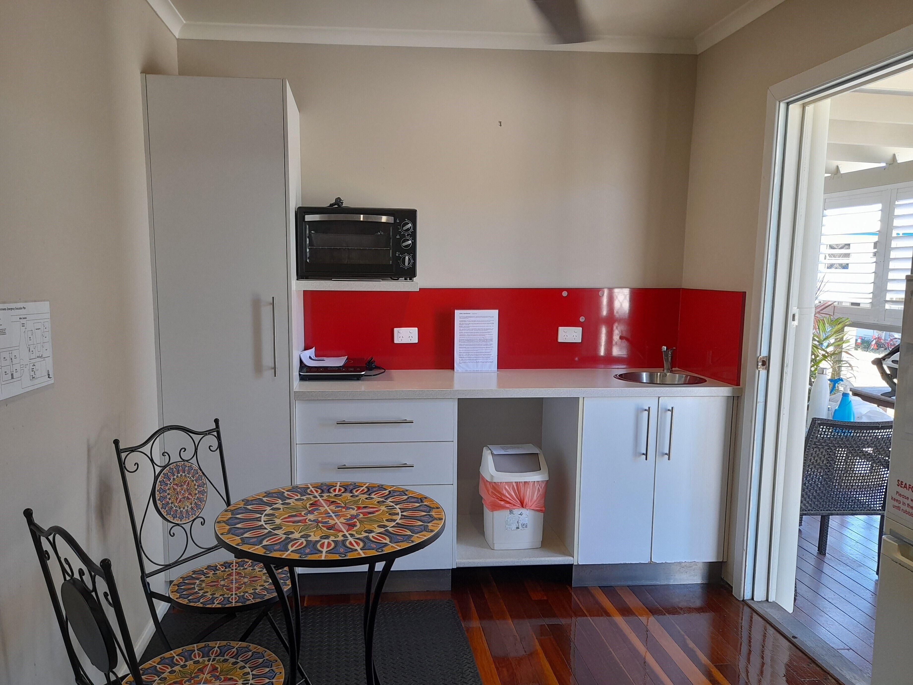 A compact kitchen with a microwave, a sink, and a small table with chairs.