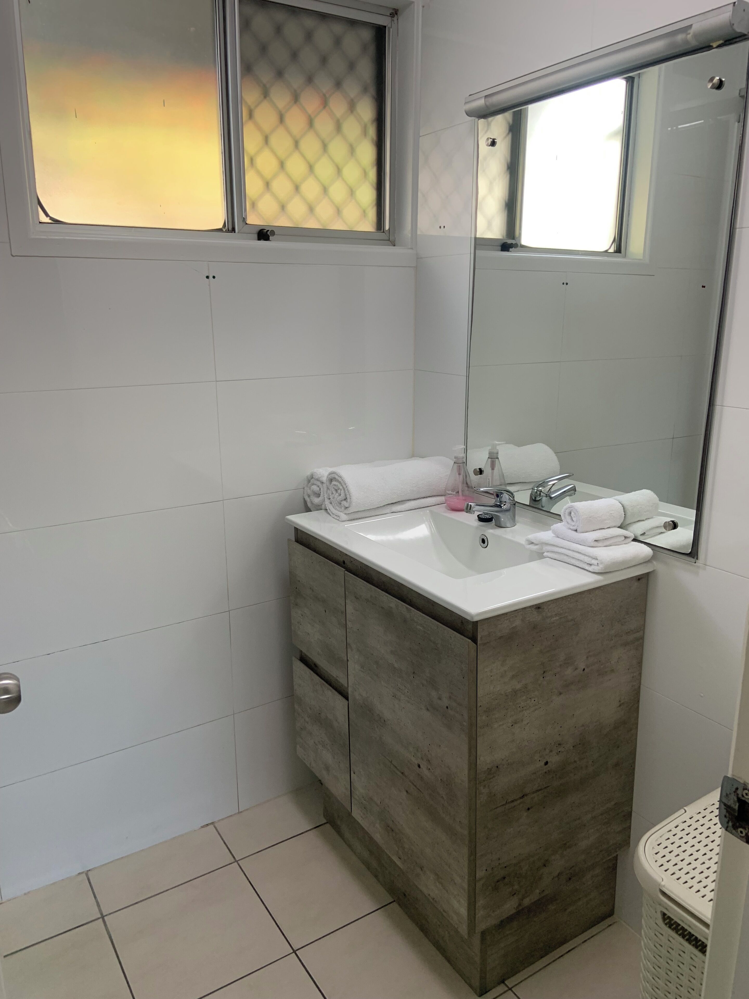 A bathroom with a white sink, a mirror, and a towel rack.