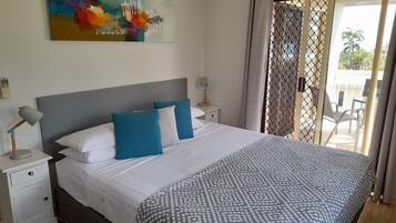 A neatly made bed with white and blue pillows, a grey patterned throw, and a modern headboard.