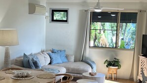 A modern living room with a sofa, coffee table, and dining area.