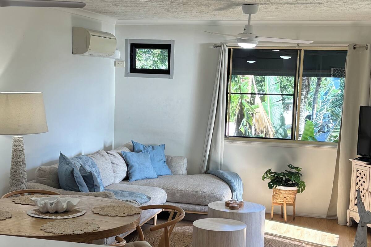 Een moderne woonkamer met een bank, salontafel en eethoek.