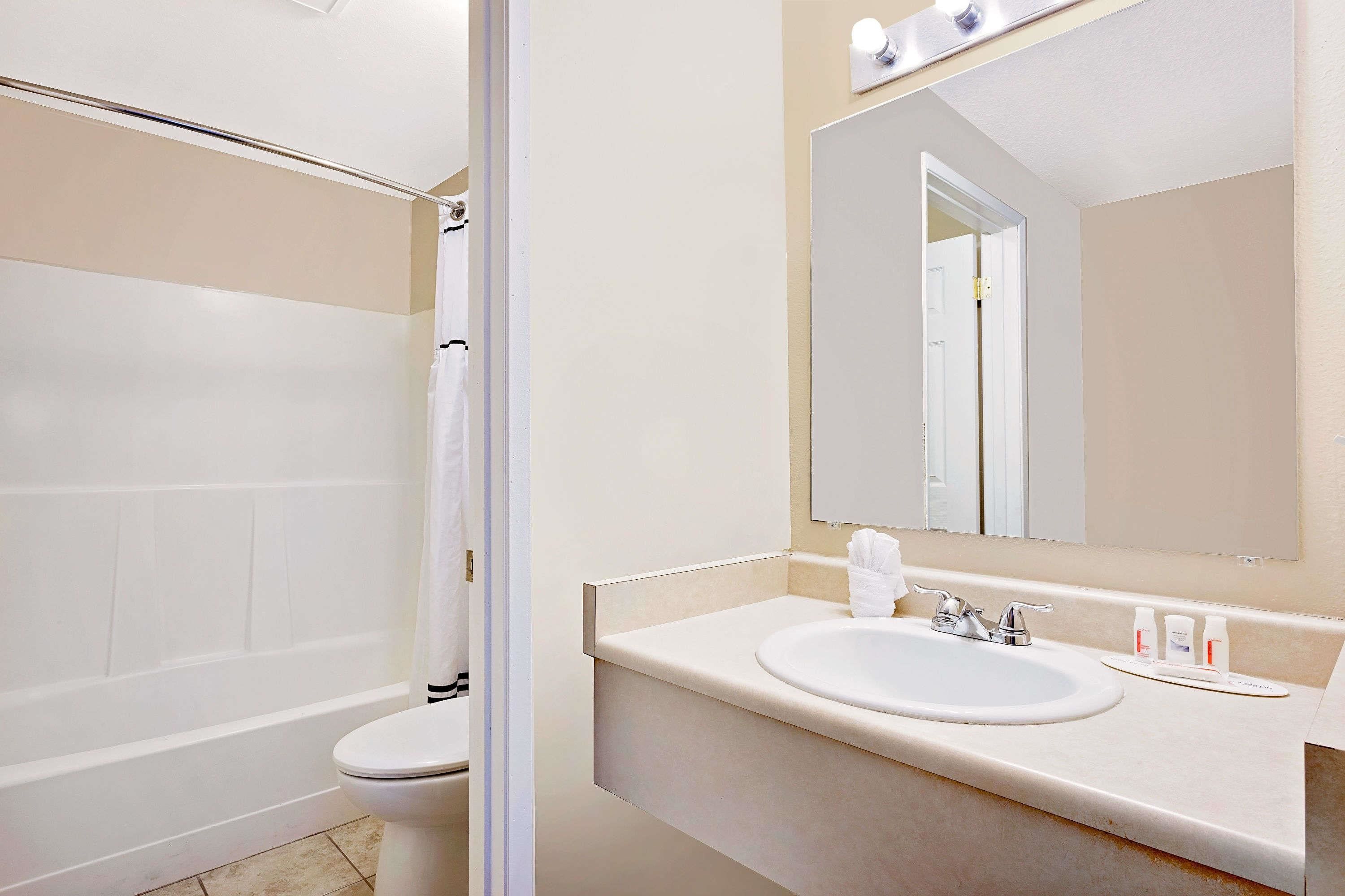 A bathroom with a bathtub, toilet, sink, and a mirror.