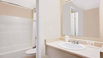 A bathroom with a bathtub, toilet, sink, and a mirror.