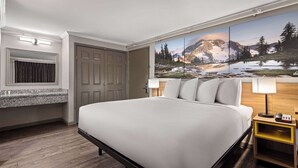 Een hotelkamer met een groot bed, een houten nachtkastje, een tv aan de muur en een deur.