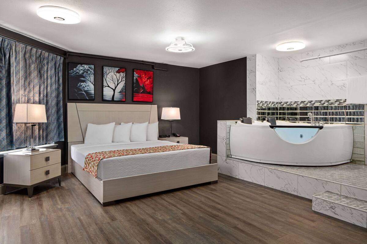 Un dormitorio moderno con una cama grande, mesitas de noche, un tocador con espejo y obras de arte en la pared.