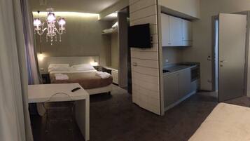 Una habitación de hotel pequeña con cama, mesita de noche y un kitchenette.