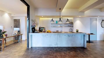 Una cocina moderna con una isla central, iluminación colgante y un salpicadero de ladrillo.