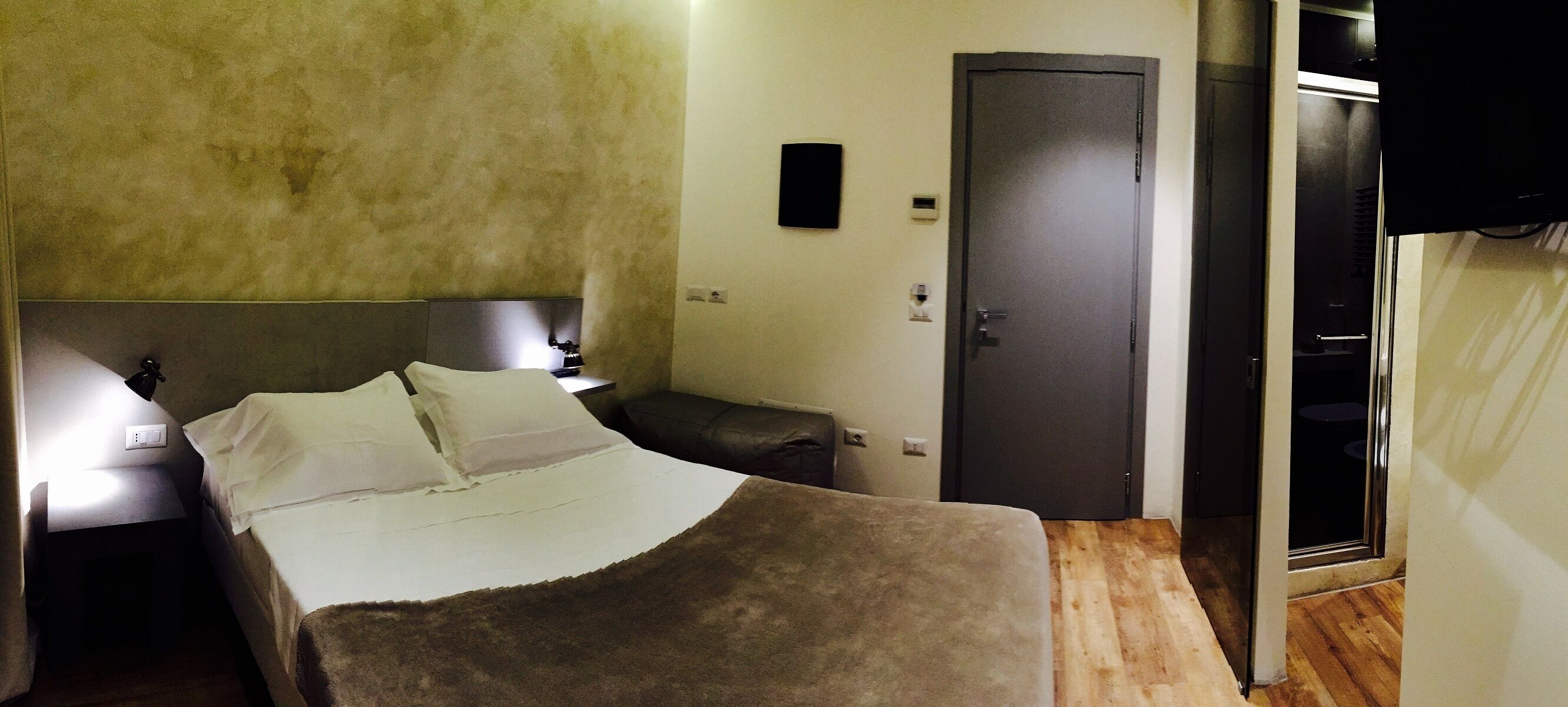 A bedroom with a bed, bedside table, lamp, wardrobe, and a television.