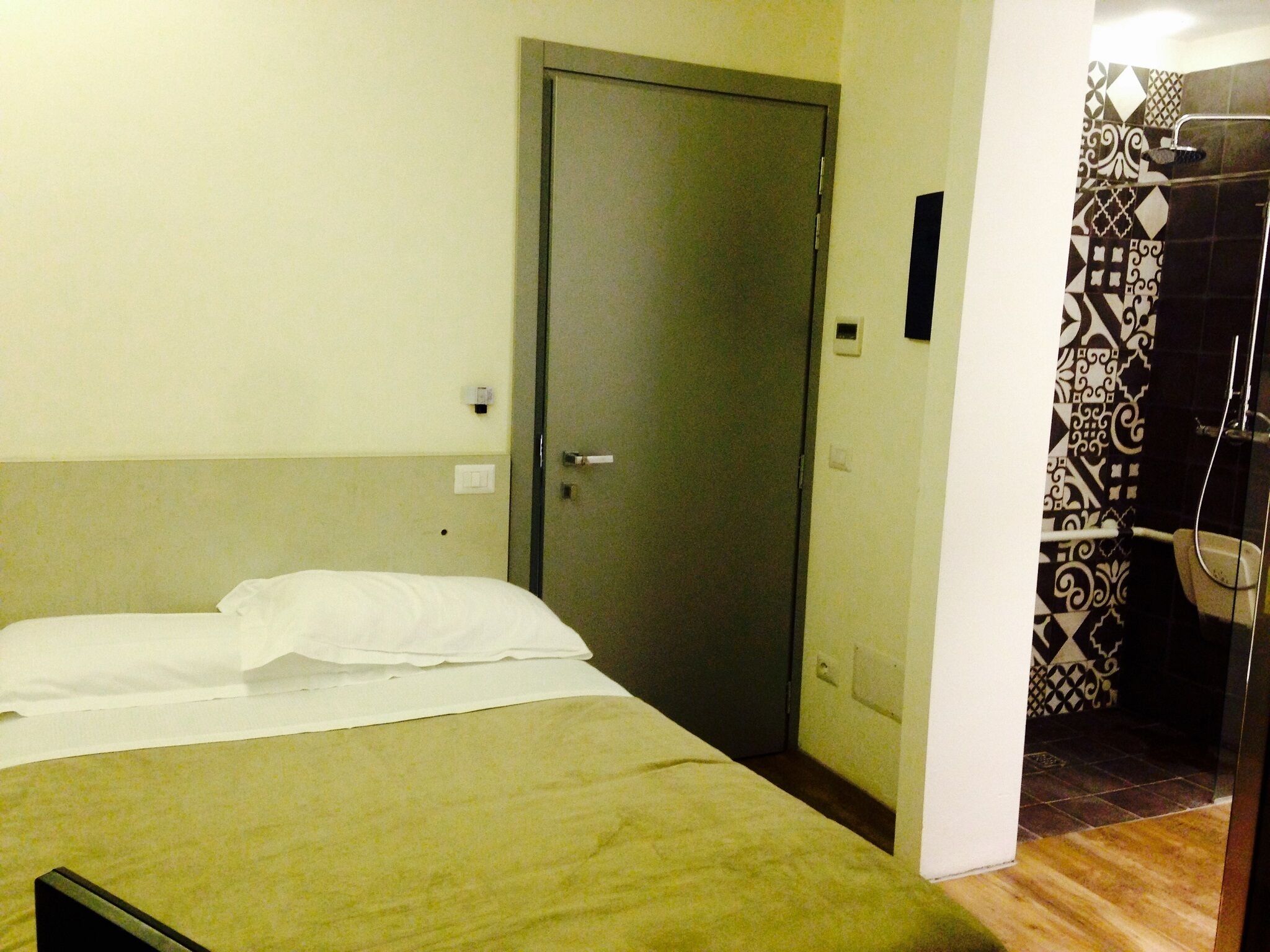 Una camera d'albergo con un letto, una porta e uno spazio doccia.
