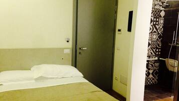 Una camera d'albergo con un letto, una porta e uno spazio doccia.