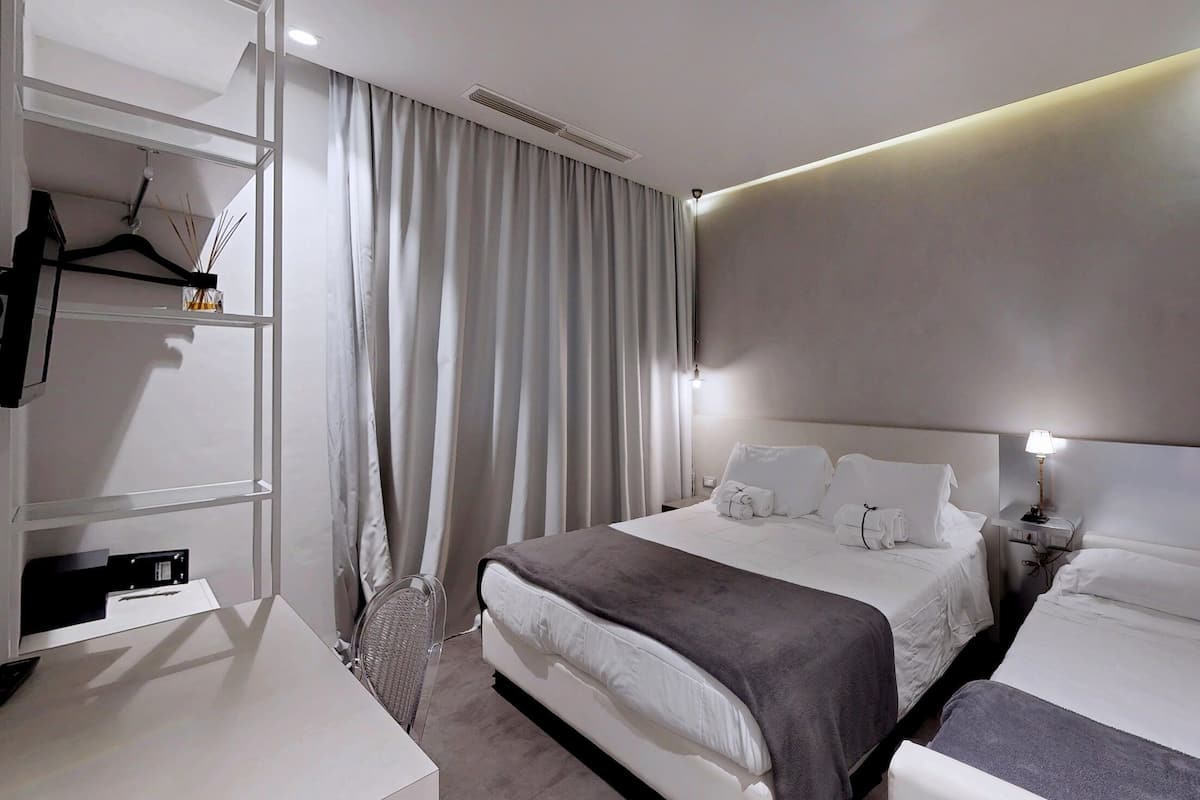 Une chambre d’hôtel moderne avec un grand lit, des tables de chevet, une armoire et un porte-manteau avec une serviette.