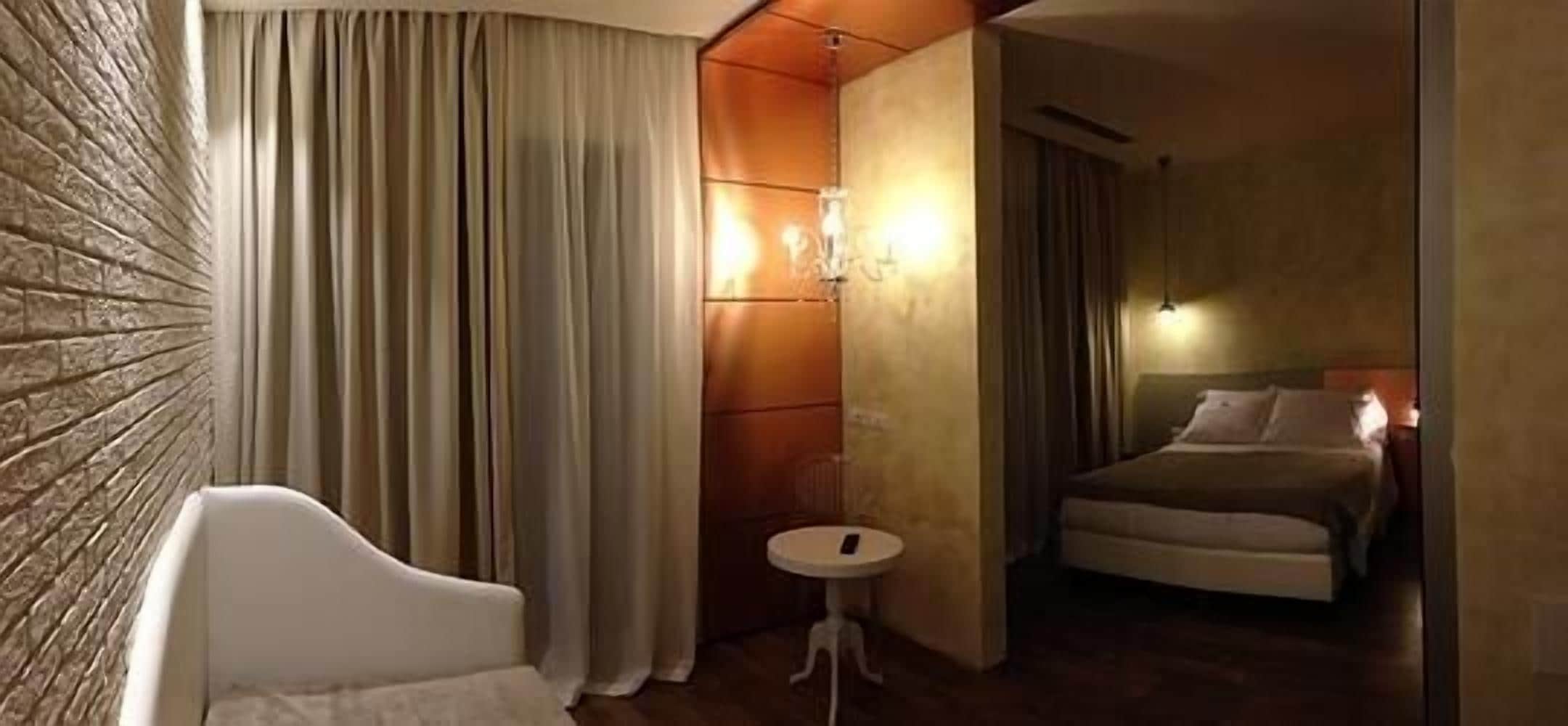 Une chambre d’hôtel avec un lit, une petite table ronde et un fauteuil blanc.