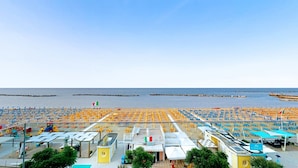 A beachside hotel with multiple sun loungers and umbrellas, a bar, and a view of the sea.