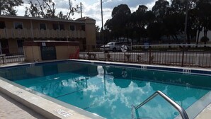 A rectangular swimming pool with a metal handrail, surrounded by a concrete deck. - Budget Lodge of Mount Dora (Mount Dora)
