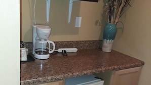 A compact kitchen with a microwave, coffee maker, and a small refrigerator. - Budget Lodge of Mount Dora (Mount Dora)