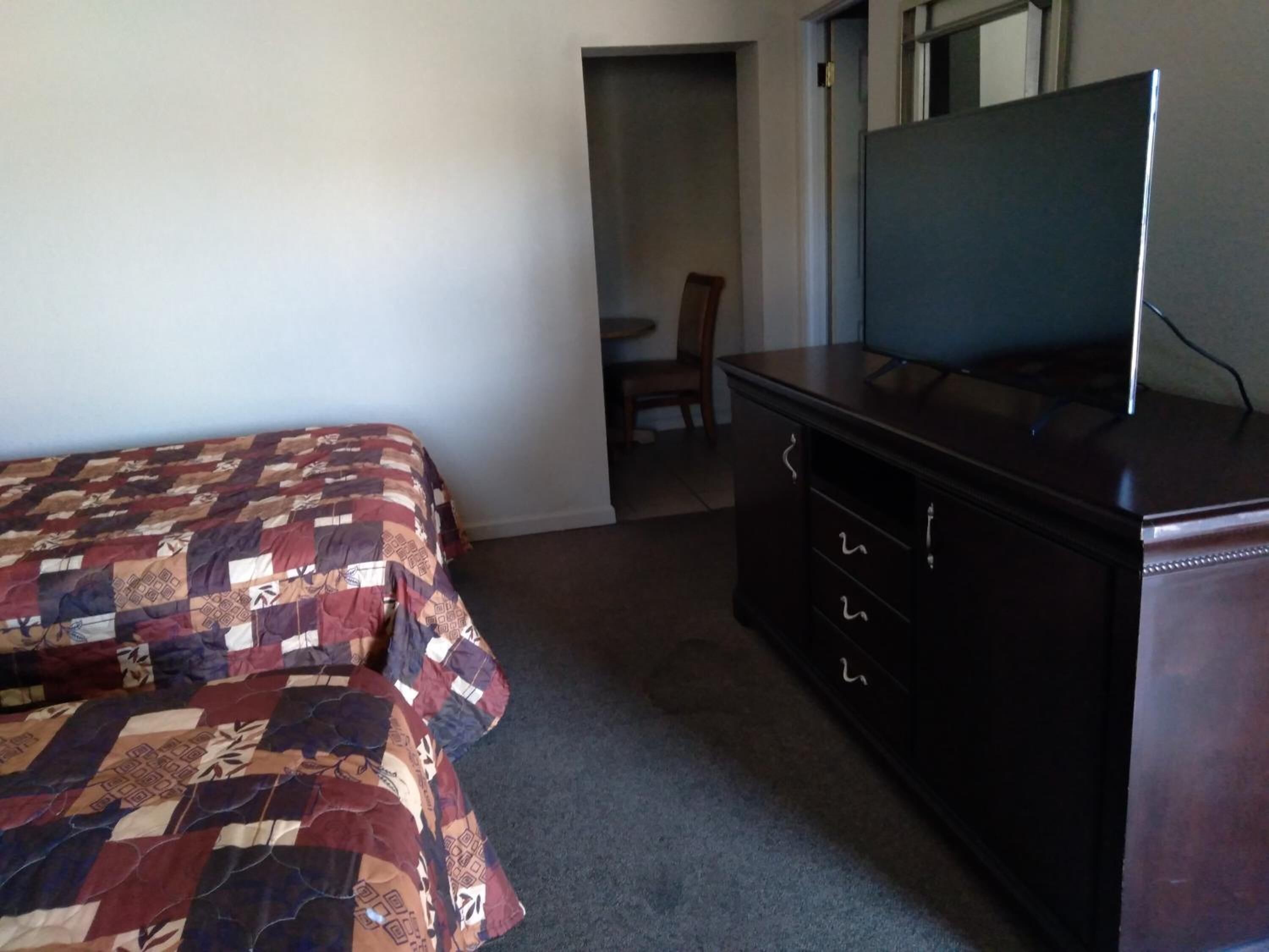 A bedroom with a bed, a dresser, and a television.