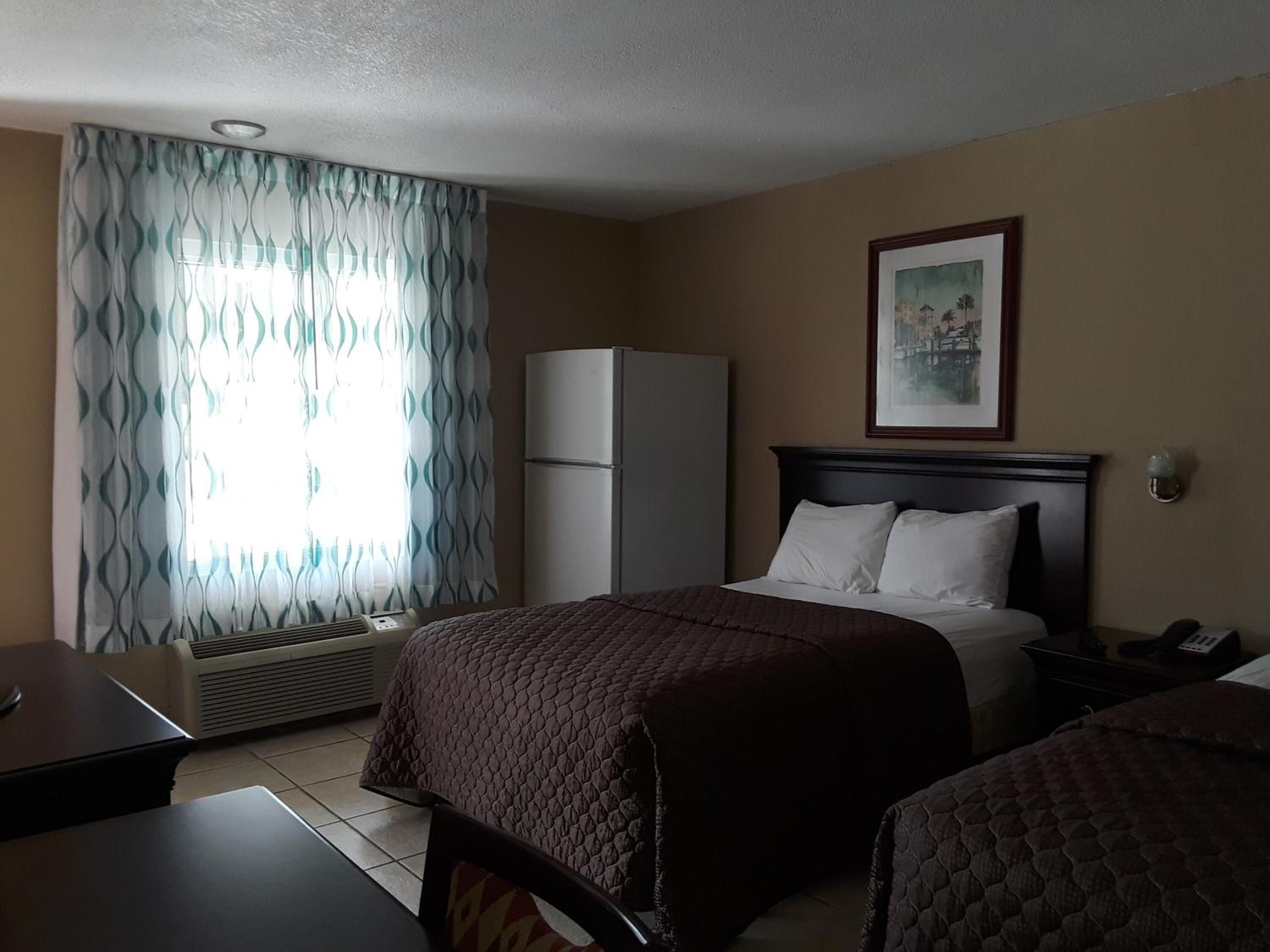 A hotel room with a bed, a desk, a chair, a wardrobe, and a window with curtains.