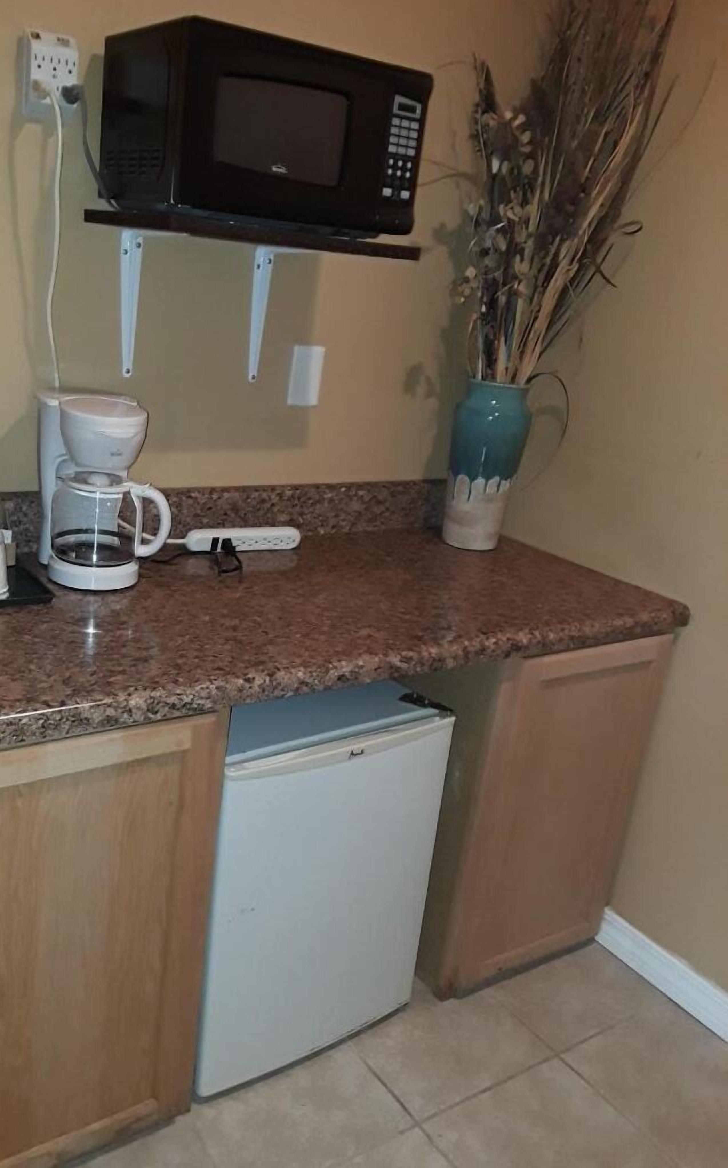 A compact kitchen with a microwave, coffee maker, and a small refrigerator.