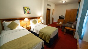 Ett hotellrum med två sängar, en tv, ett litet bord och en stol.