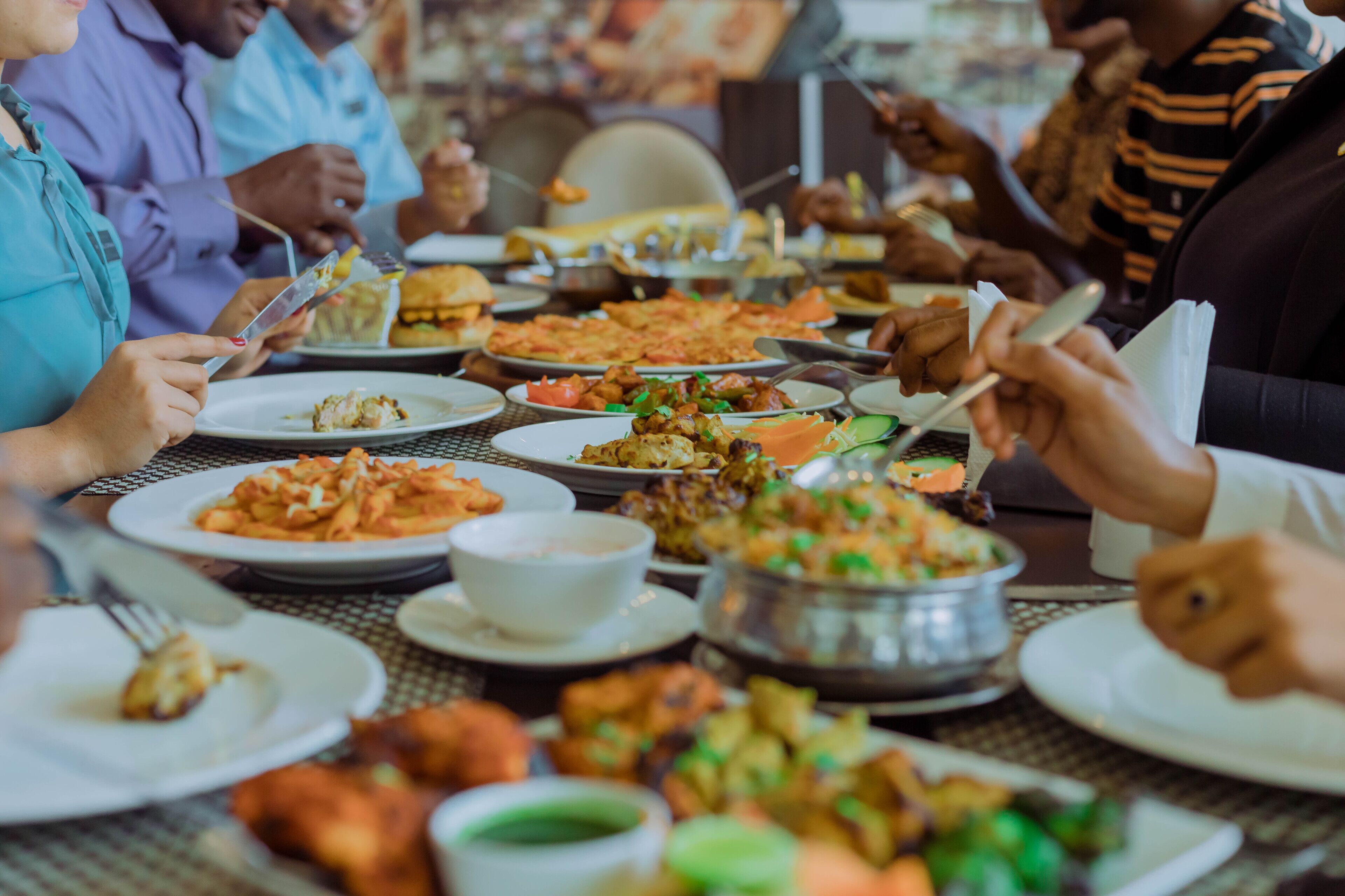 A group of people dining at a table with various dishes and utensils.