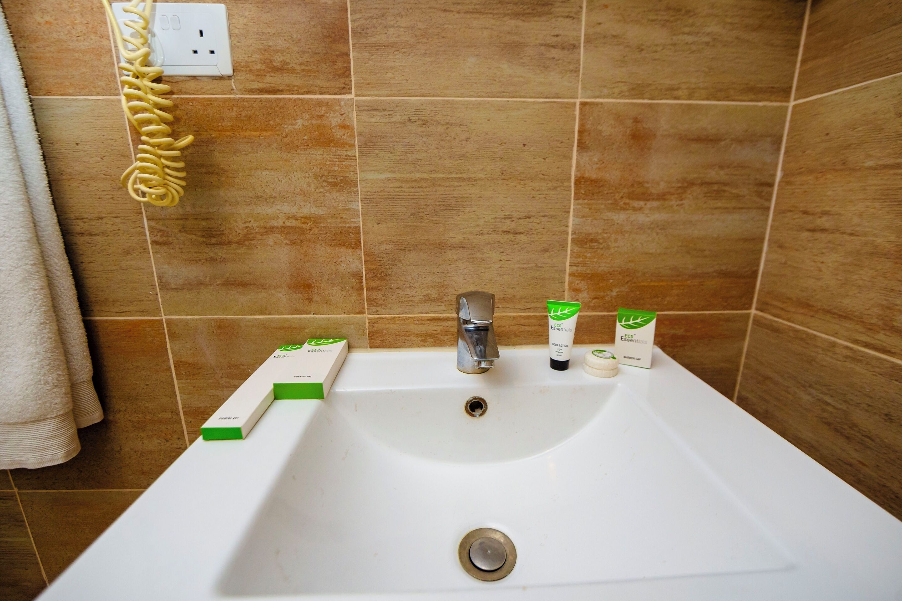 Un lavamanos con un portalavabo verde y blanco, una botella verde y blanca de loción corporal y una caja verde y blanca de champú.