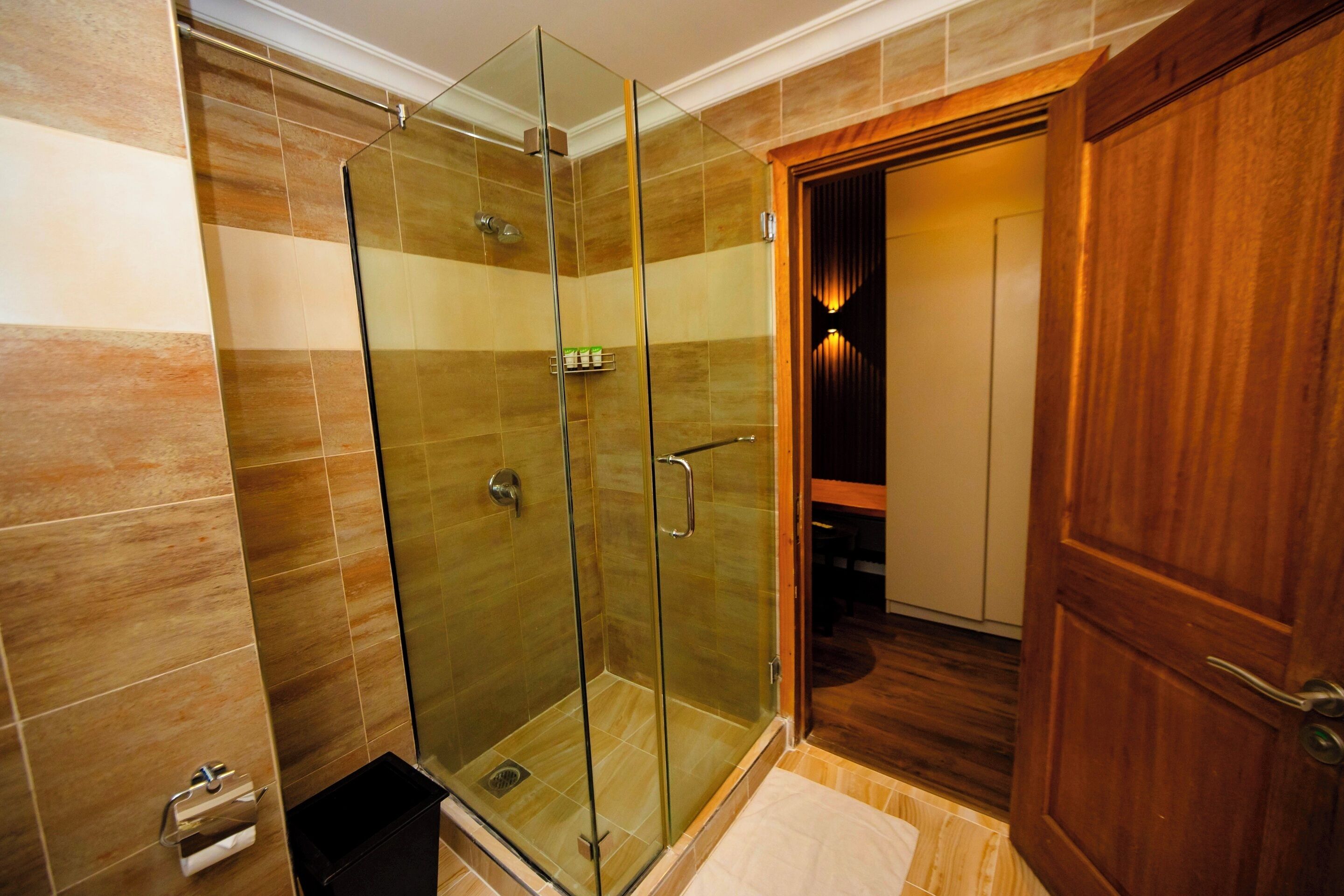 A glass-enclosed shower with a wooden door and a towel rack.