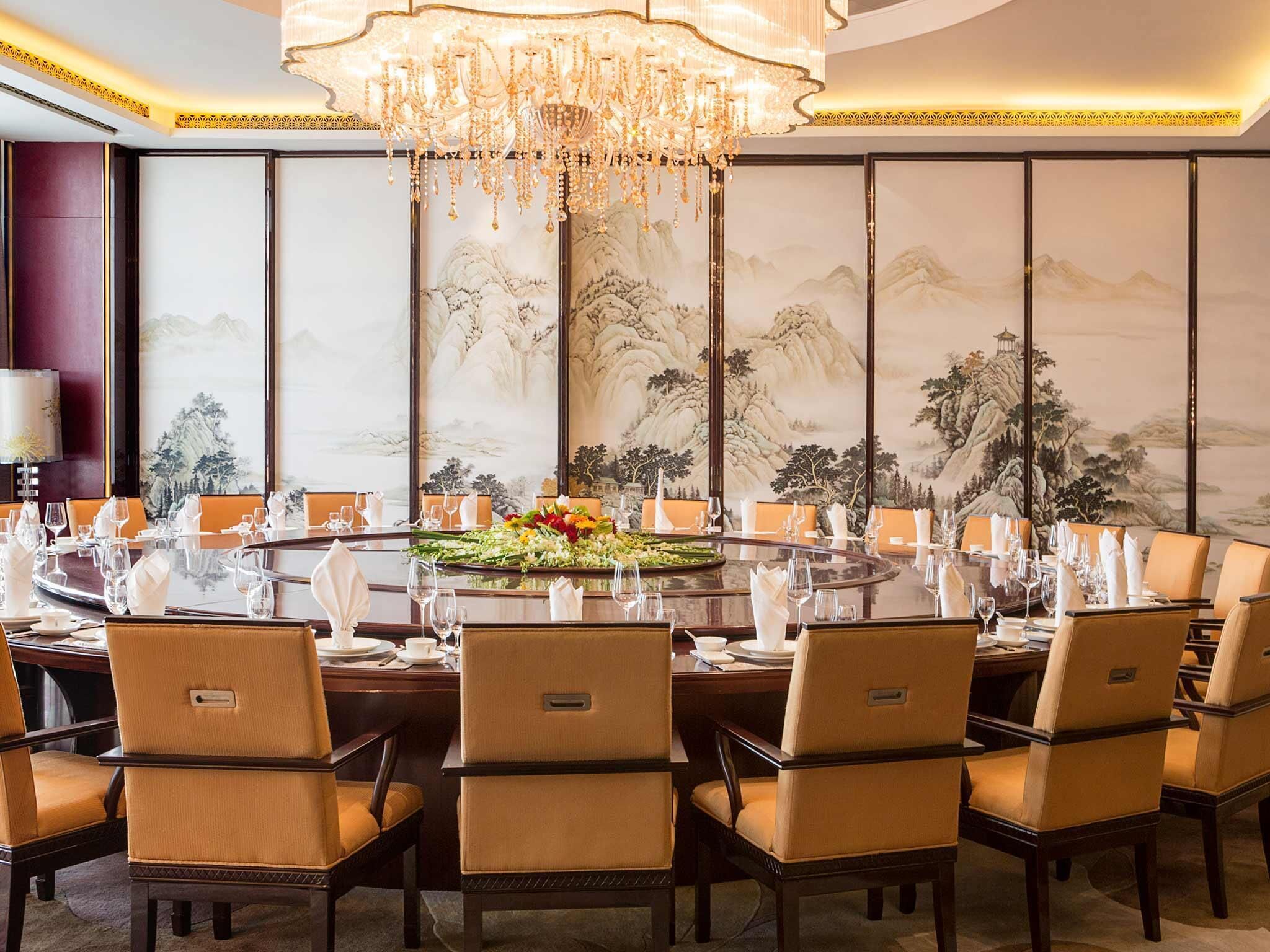 A formal dining room with a round table, multiple chairs, and a chandelier.