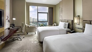 A hotel room with two beds, a desk, a chair, a TV, and a large window with a city view. - Pullman Weifang (Weifang)