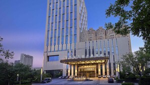 A hotel with a modern facade, a prominent entrance, and a parking area. - Pullman Weifang (Weifang)