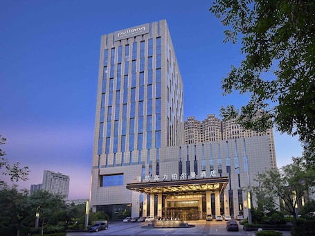 A hotel with a modern facade, a prominent entrance, and a parking area.. Pullman Weifang