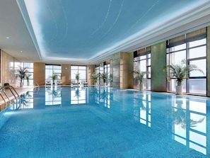 An indoor swimming pool with clear water, large windows, and potted plants. - Pullman Weifang (Weifang)
