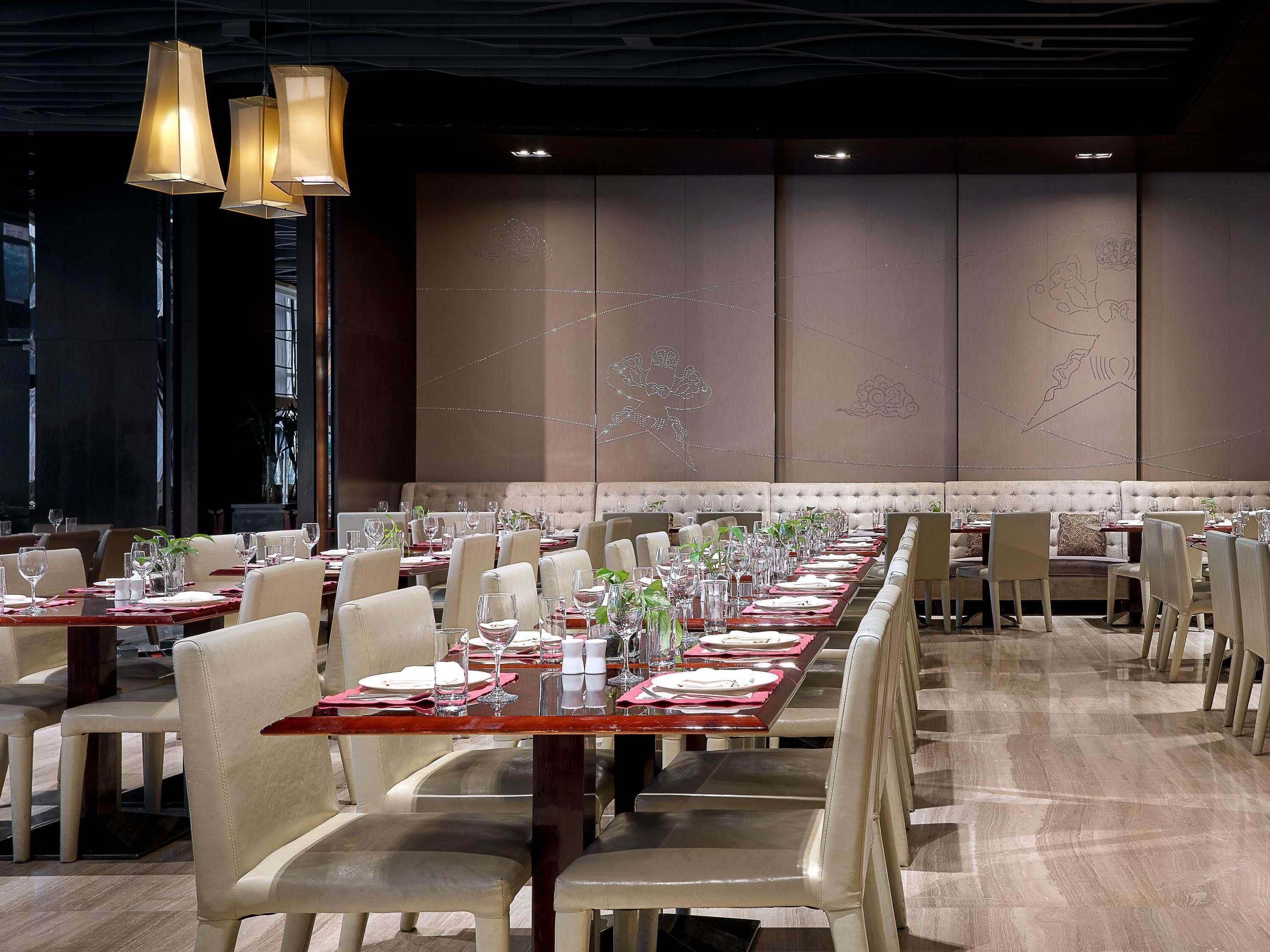 Un restaurante con mesas largas, sillas e iluminación colgante.