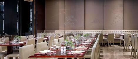 Un restaurante con mesas largas, sillas e iluminación colgante.